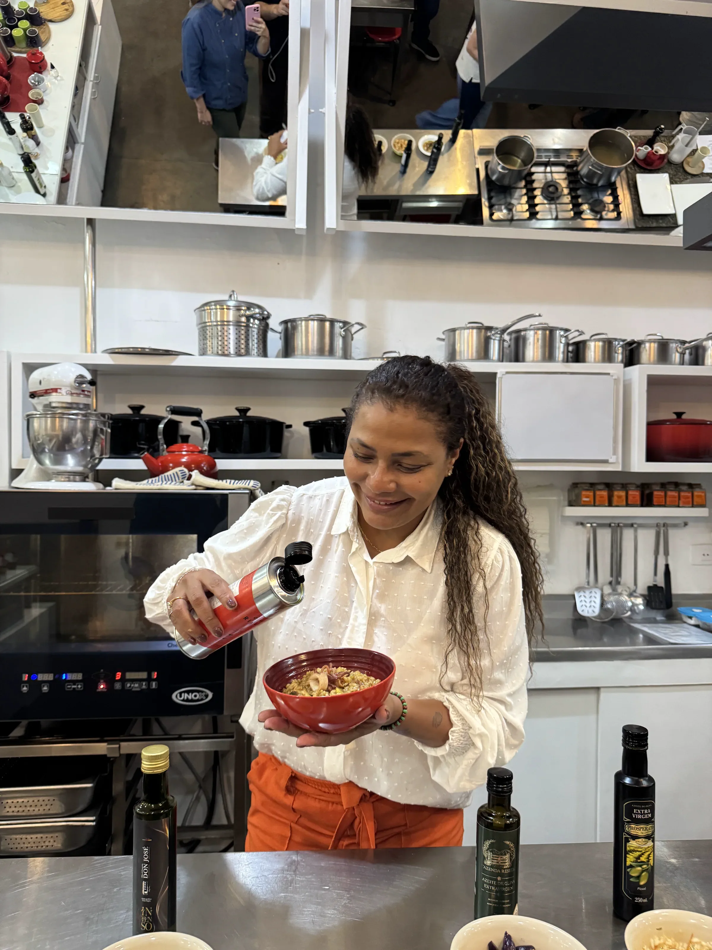 Aluna aplica azeite em um prato durante a aula prática na cozinha